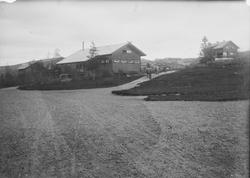 I forgrunnen sees en gruslagt vei eller gårdsplass. I midten