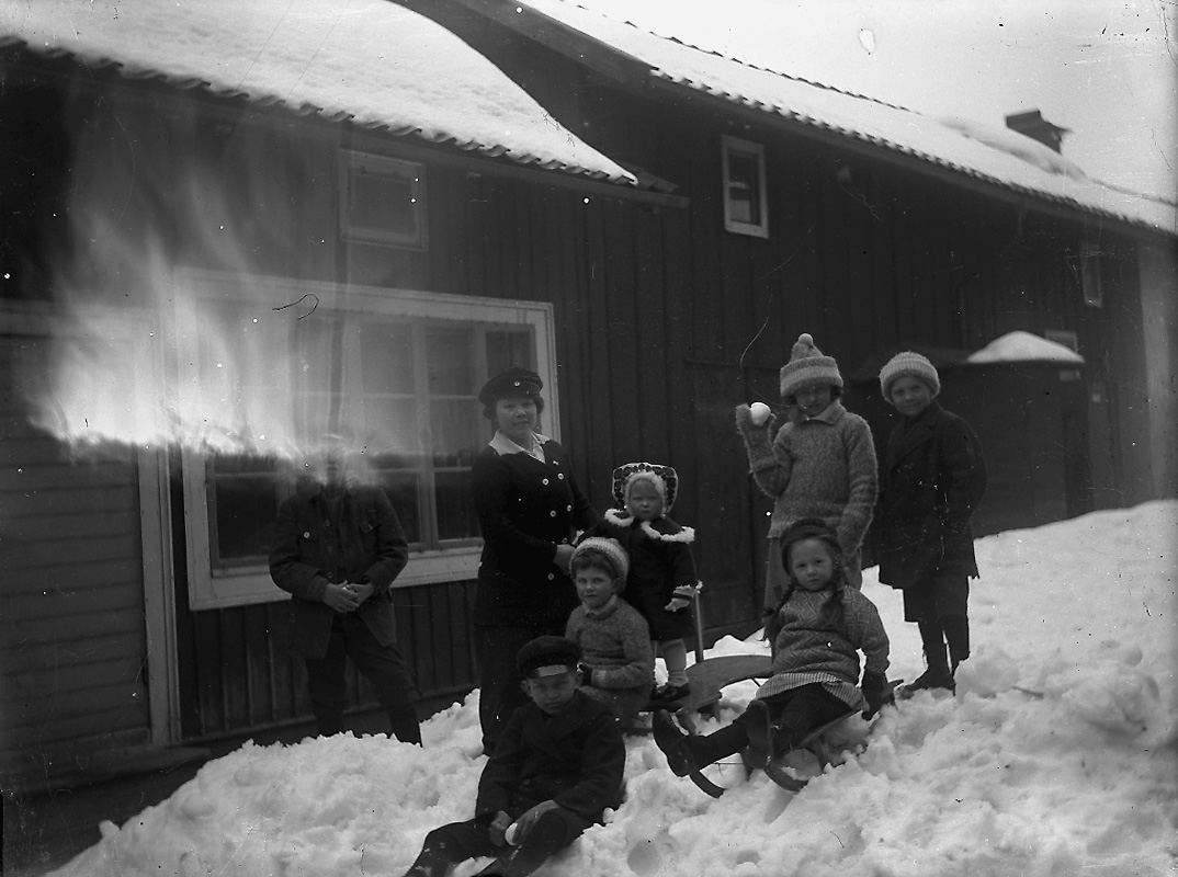 Vintermotiv, en kvinna och sju barn.
Troligtvis på gården på Kungsgatan 33, Lindesberg.