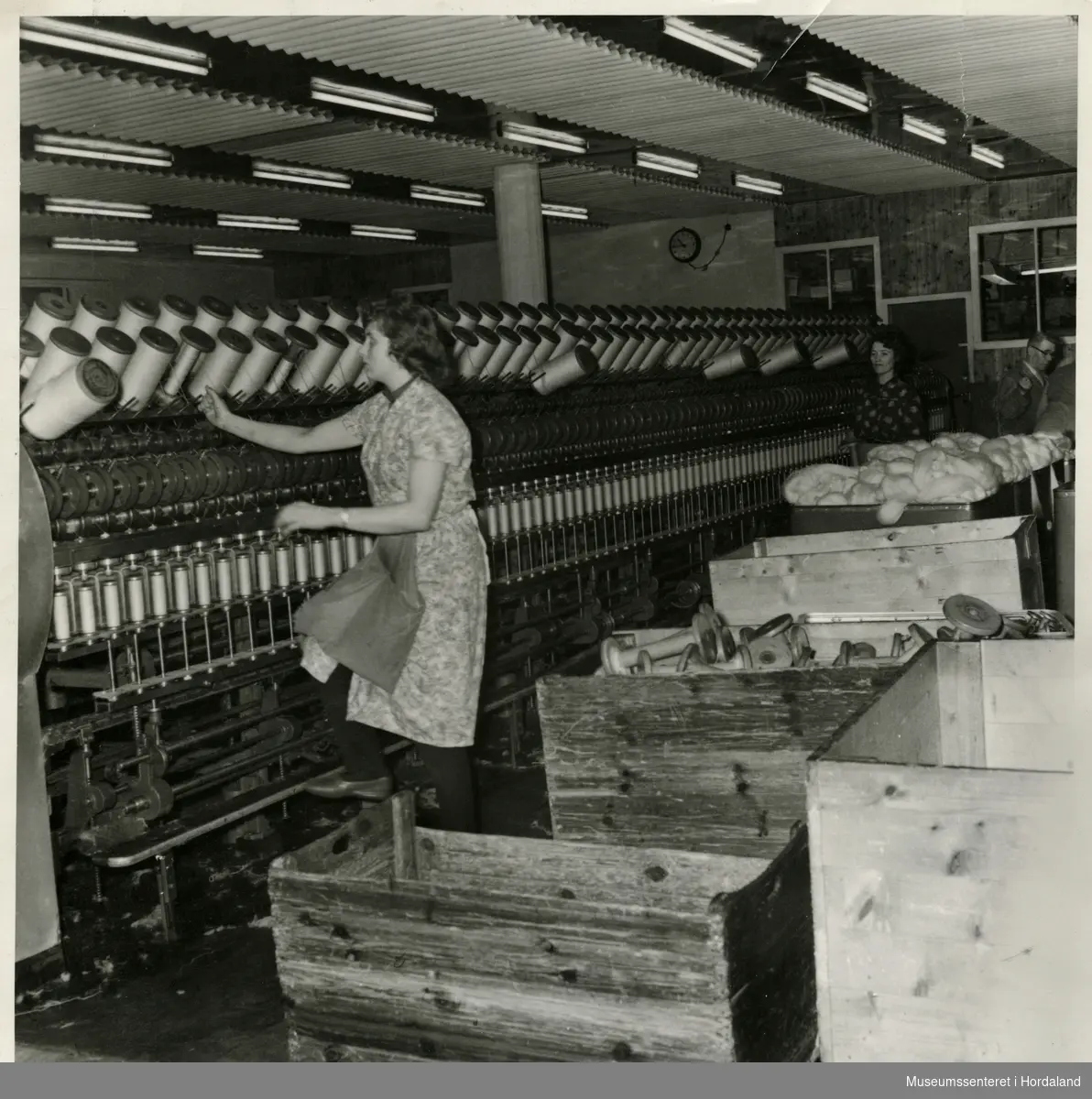Kvinne arbeider ved spinnemaskin i produksjonslokala til Dale Fabrikker. Fotografiet er merka "Flyer spinnemaskin".