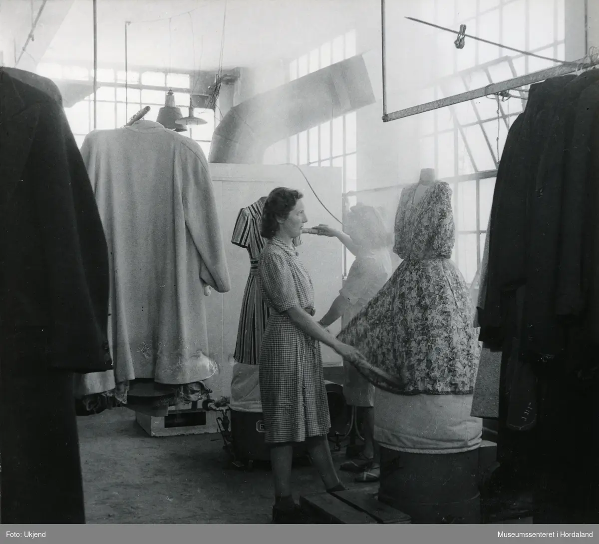 To kvinner arbeider ved Wilhelm Kahrs Kemisk Renseri & Farveri, Bergen. "Amerikanske apparater i virksomhet."