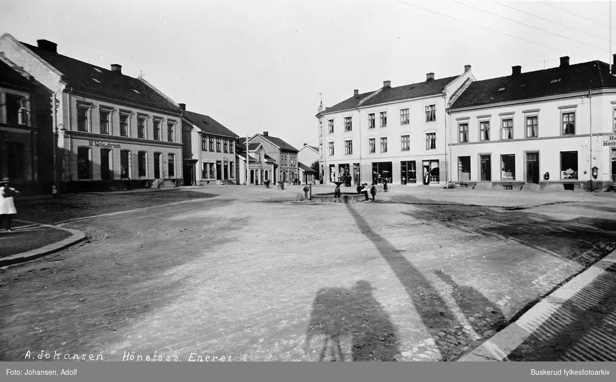 N. Torg i Hønefoss
Bildet er at av 585 bilder som ble vist under Frognerutstillingen i Osli 1914.
Skyggen av fotografen viser at han bruker et reisekamera med negativformat på 18x24 cm.