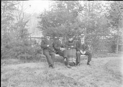 Gruppebilde på benk ute, en kvinne, tre menn