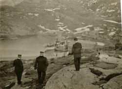 Tre offiserer i land, ved kaien ligger dampskipene 'Aafjord'