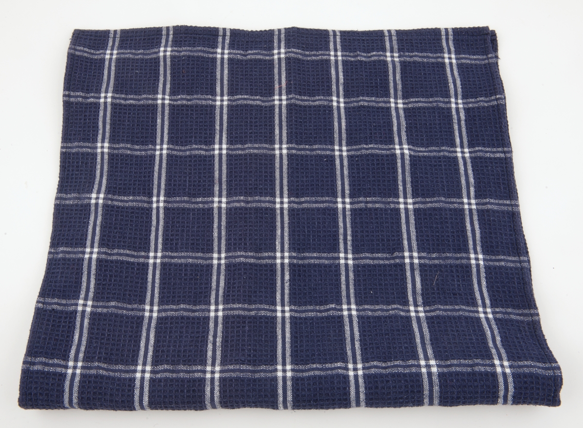 Mørkeblått kjøkkenhåndkle med hvitt rutemønster.