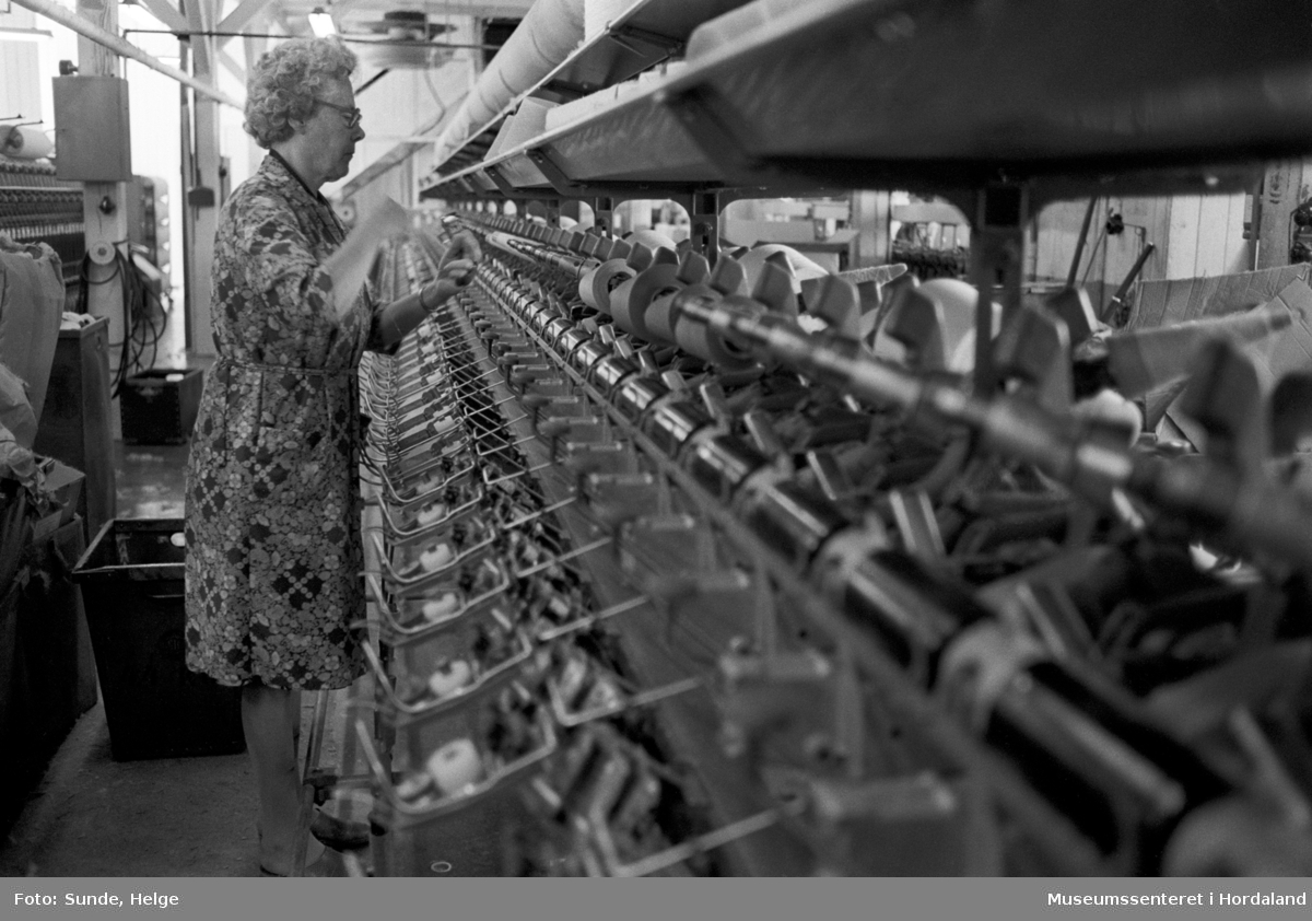Arbeidsliv ved Salhus Tricotagefabrik i Salhus, Bergen i 1976. Kvinne arbeidar ved spolemaskin i 1910-bygget på Salhus Tricotagefabrik.

T.v: Magda Sellevold