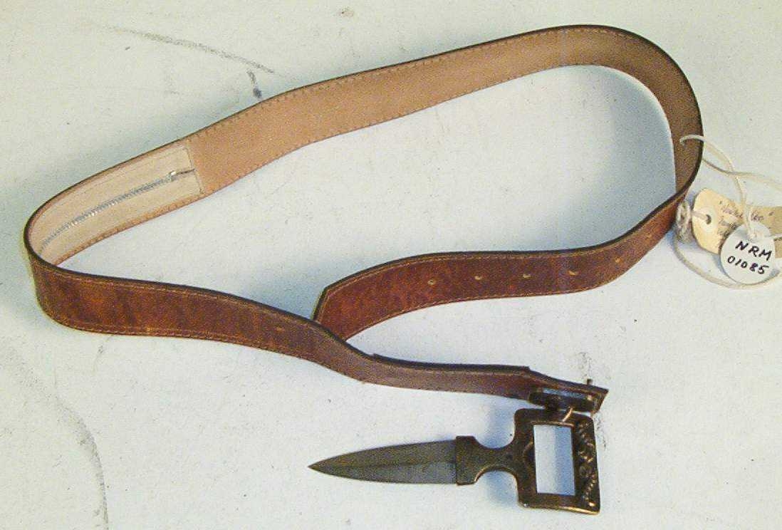 Spenne med kniv og hylster med glidelås for stoff (narkotika).
Knivbladet er 7.5 cm langt og 2.5 cm bredt.