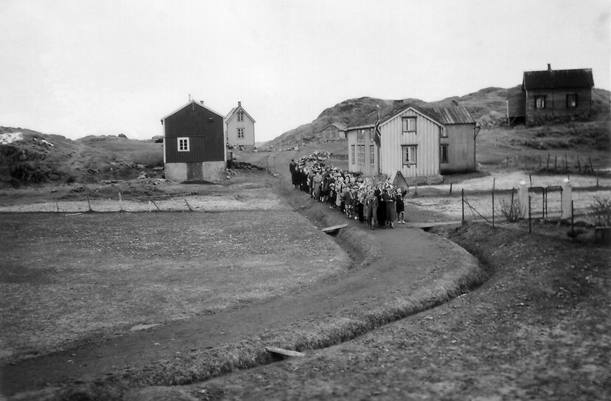 17. maitog på Meløyvær. Gårdsbebyggelse i bakgrunnen.