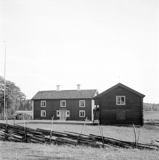 Lerbäcks hembygdsgård fotograferad den 24 maj 1937. Till vänster står hembygdsgårdens huvudbyggnad. Det är en bergsmansgård från år 1843, som flyttades till Lerbäcks hembygdsgård år 1933. Till höger om huvudbyggnaden syns en gammal loftbod från 1700-talet, som flyttades år 1929 till hembygdsgården. Längst fram syns en gärdsgård.
