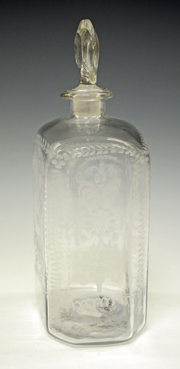 Glasskaraffel i klart glass - firkantet form, med avbrutte hjørner (skrå), slik at flasken eg. har 8 kanter. Gravering på alle sider - midt på begge de store flatsidene er det gravert et dyr (hjort eller rådyr), ellers vanlige ranker, blomster og blader.
Flasken har glasspropp - virker original. Ingen skader.

Stor glassflaske av typen kantineflaske. Gravert. Usikker produsent - kan det være Gjøvik eller Hurdal? 1790-1820 ca.