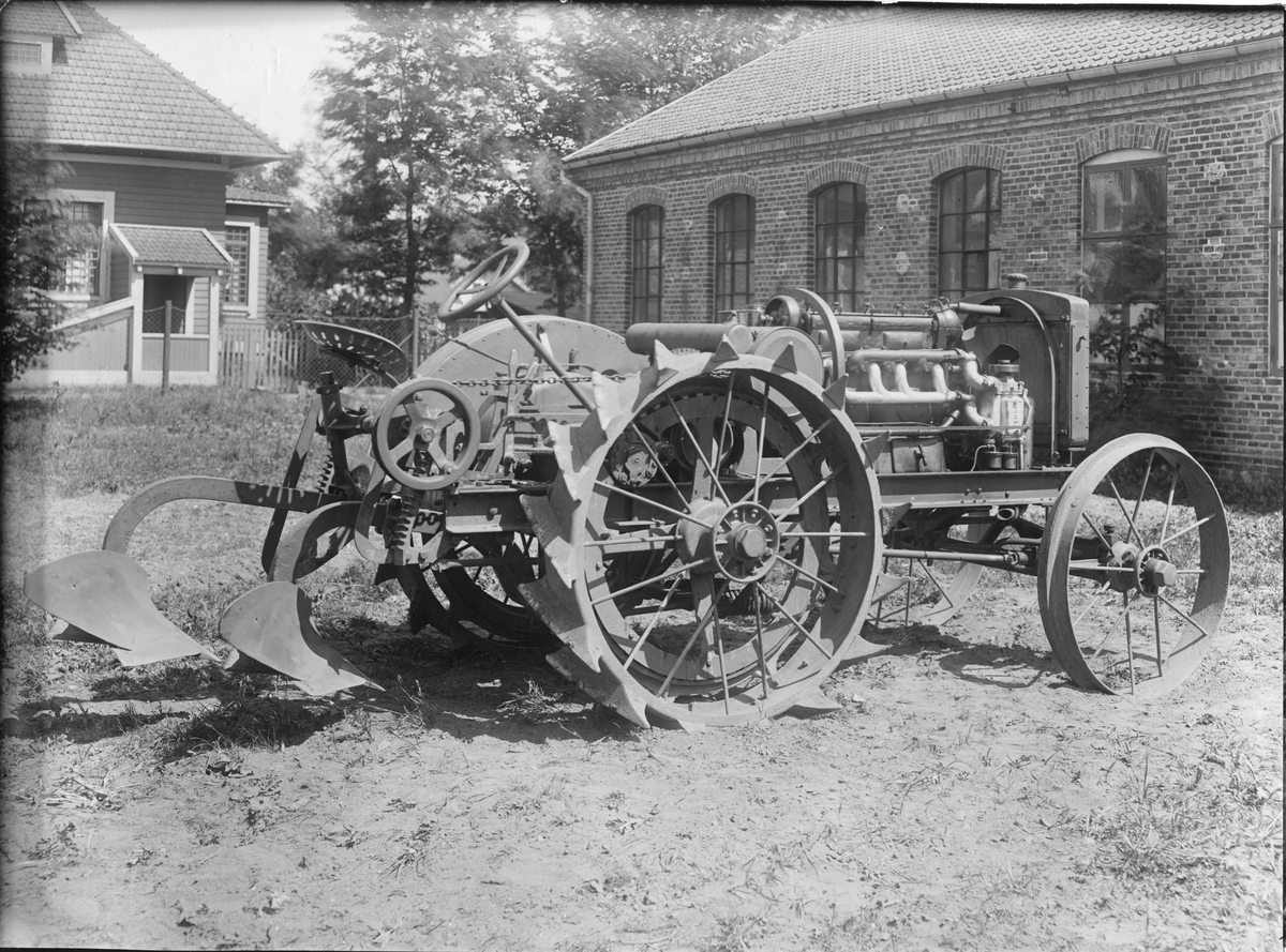 Traktorn är tillverkad ca 1921 av Svenska Motorplogsfabriken i Halmstad. Traktorn är fotograferad utanför fabriken i Halmstad.