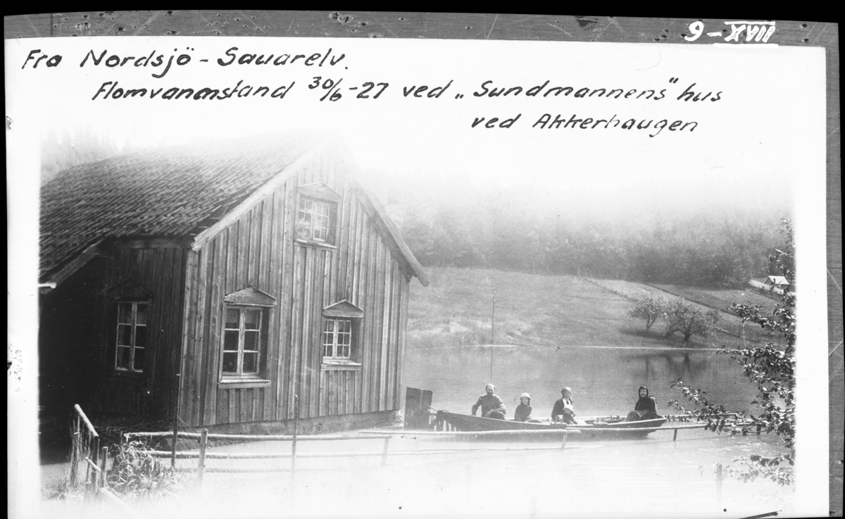 Ved Akkerhaugen jernbanestasjon (på den andre sida av elva). "Flomvannstand 30.06.1927 ved 'Sundmannens' hus ved Akkerhaugen. Det er ferjemannens stue som sees på fotografiet og i båten sitter ferjemannen med familie".