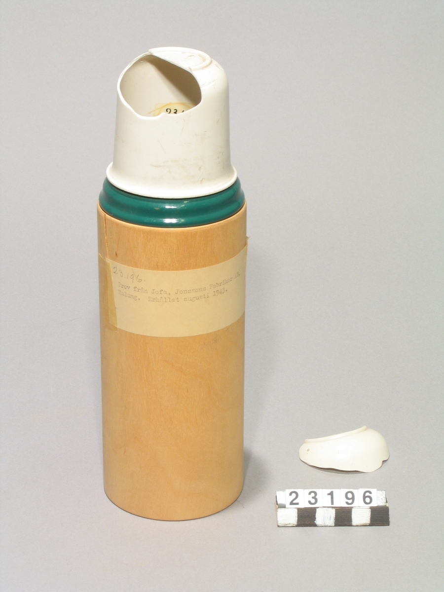 Fodral av trä och lackerad bleckplå, till "termos"-flaska. Med etikett märkt: "Prov från Jofa, Jonssons Fabriker AB, Malung. Erhållet augusti 1943"