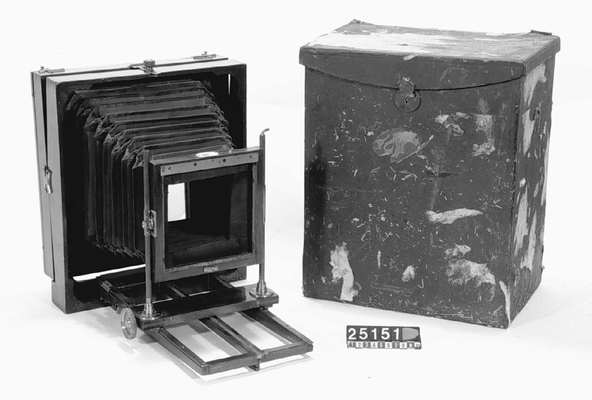 Bälgkamera, resekamera av mahogny, för plåtar, 18 x 24-format. Fällbart bakstycke. Jämte fodral. Objektiv med bräde och kassetter saknas.
Tillbehör: Väska.
