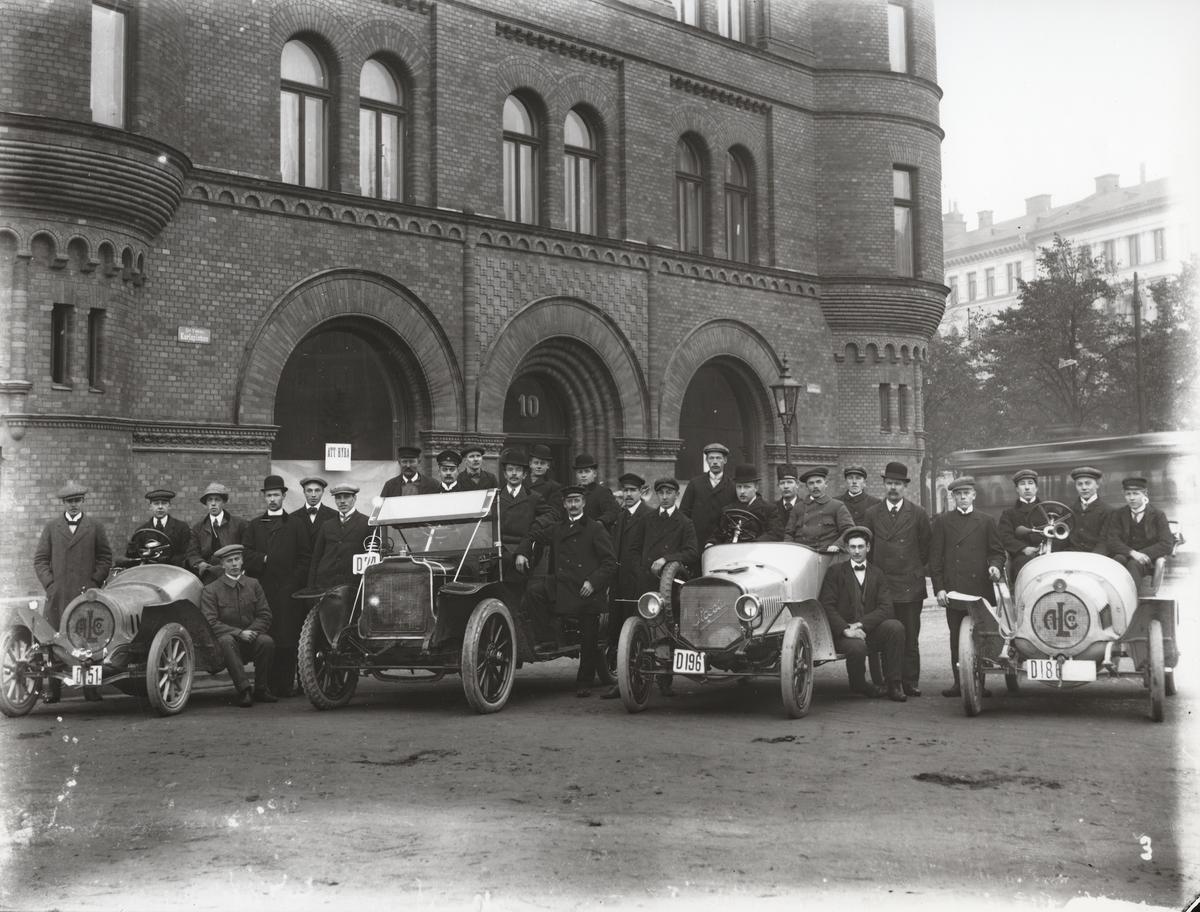 Elever vid Eric Lundviks körskola, samlade kring automobiler framför huset Karlaplan 10, omkring 1915-1920.