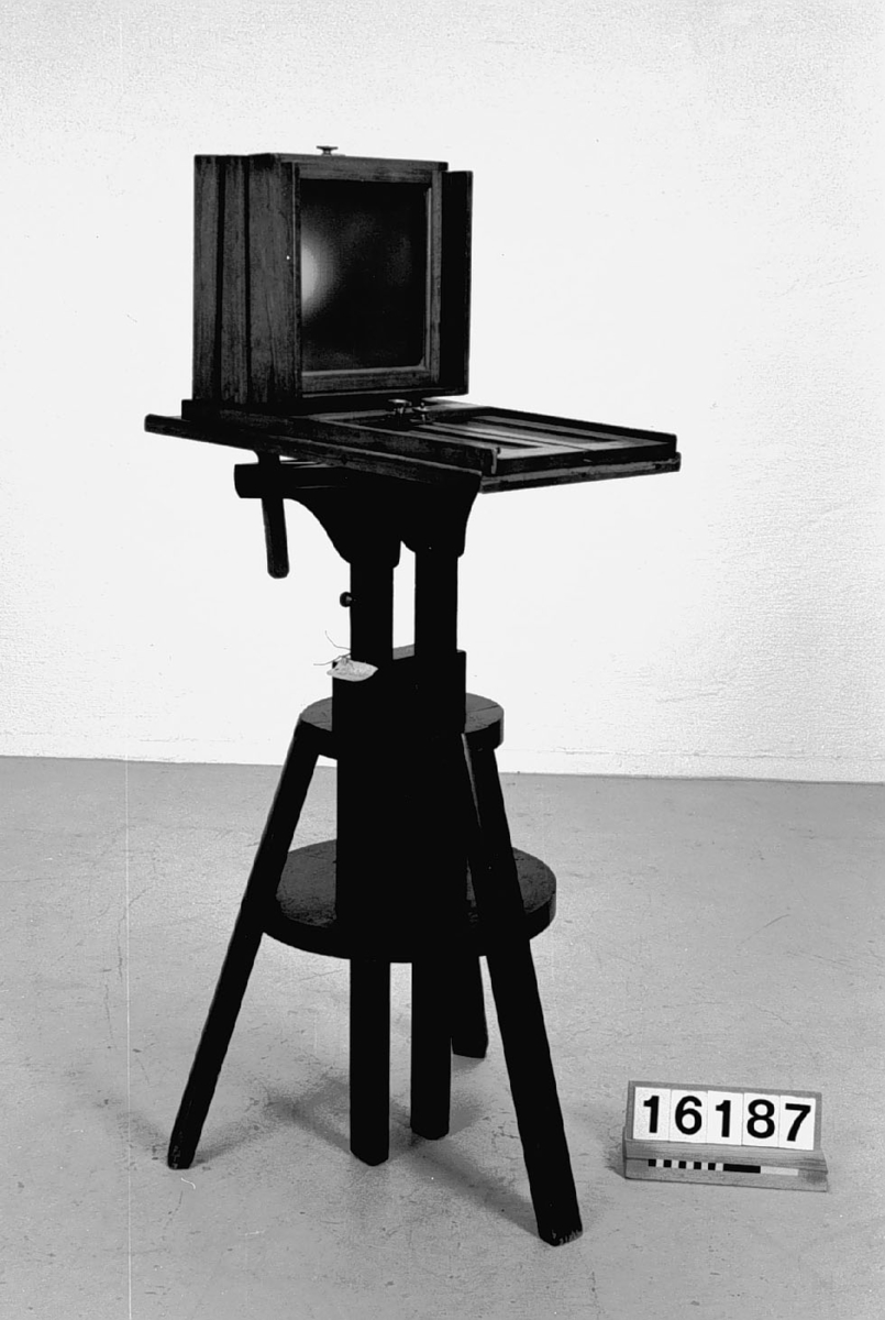 Ateljékamera av trä, för plåtar, på stativ med anordning för kamerans inställning, 18 x 24-format. Objektiv saknas.