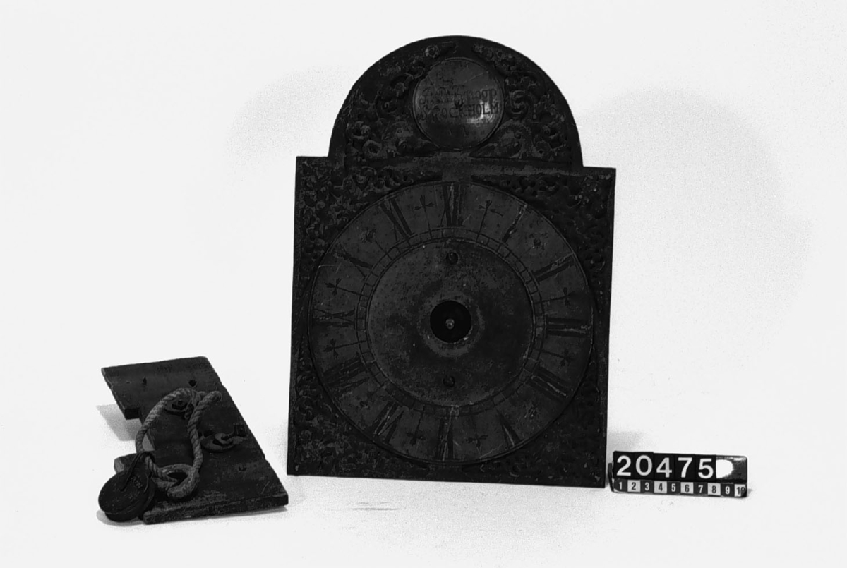 Verk och urtavla till golvur. Text i medaljong över urtavlan " J.C. Knoop, Stockholm, 1873". Ornamenten runt medaljongen trasiga. De medföljande loden hör troligen ej till uret.
