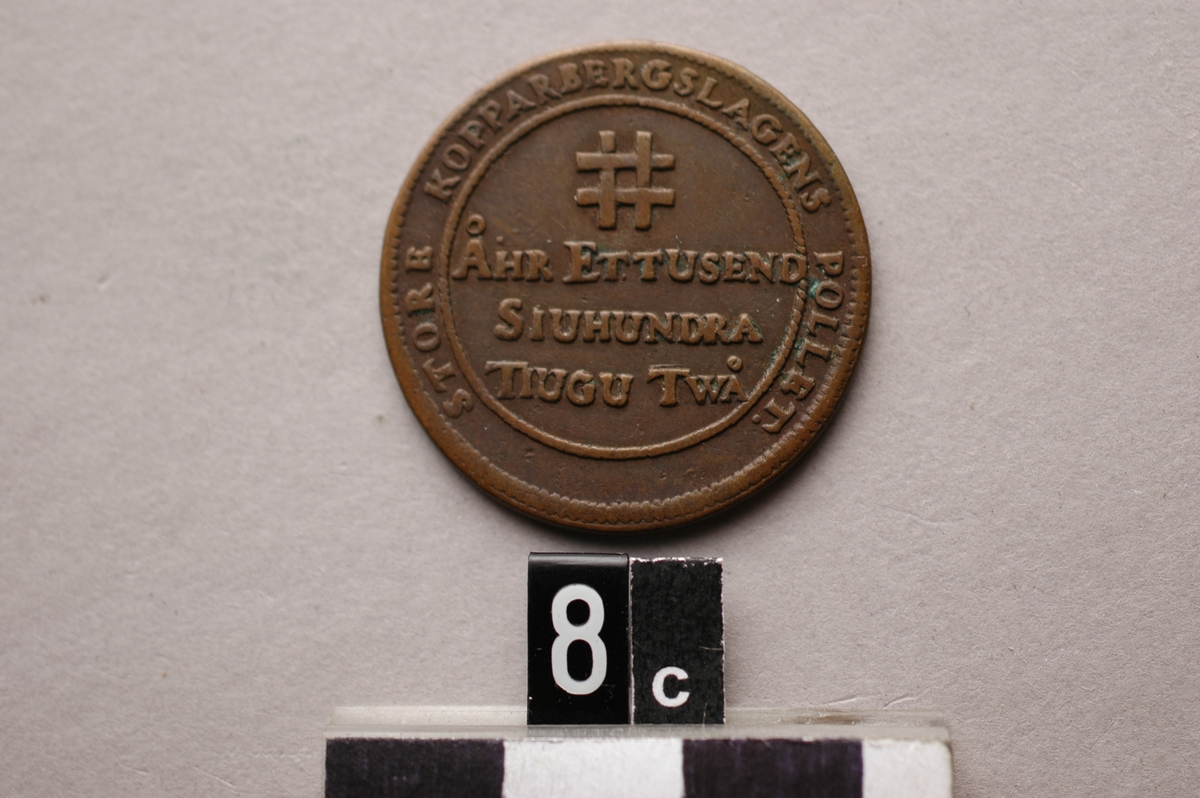 Mynt med inskrift: "Gud gifwer malm, men kåhlen tryta". Stora Kopparbergs Bergslags enskilda kopparmynt eller s.k. myntpolletter.