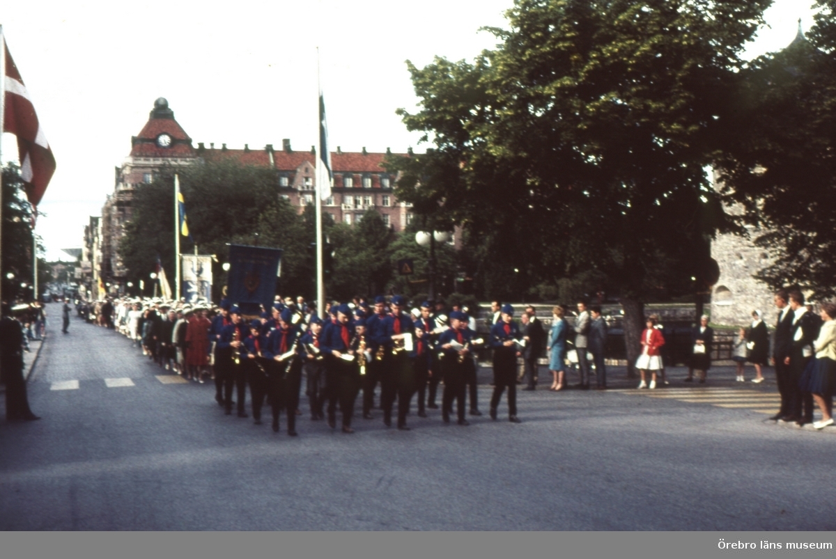 Parad på Storbron med musikorkester och folk. Centralpalastet i bakgrunden.