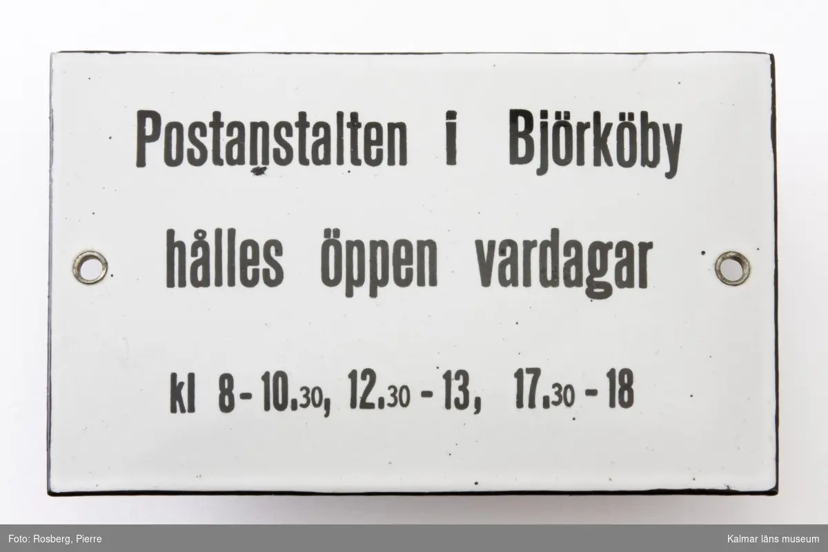 KLM 44463:41. Skylt, metallskylt, emaljerad. Har varit placerad på Björköbys järnvägsstation. Text: Postanstalten i Björköby hålls öppen vardagar kl 8-10.30, 12.30-13, 17.30-18.