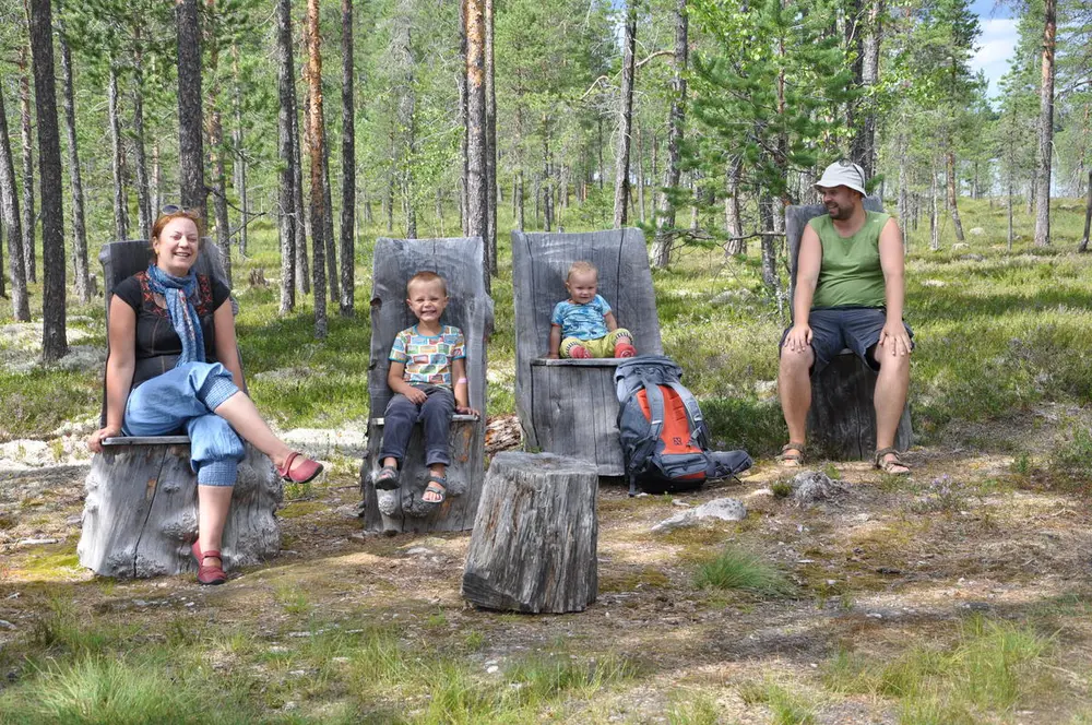 Familie sitter å hviler på trestubber og smiler til kamera.