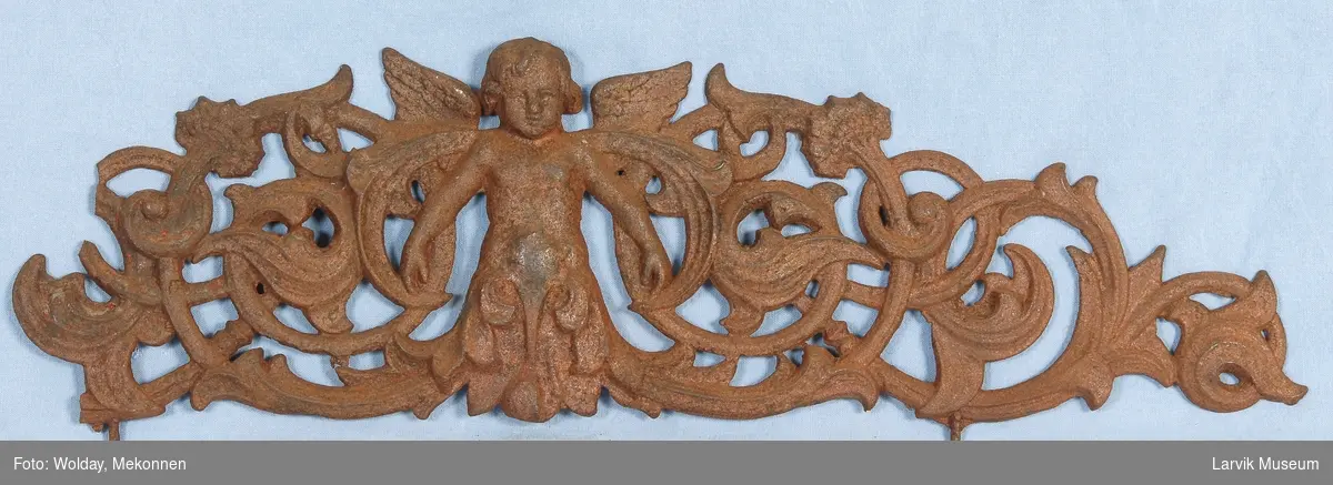 Midtstil barnefigur i form av engel omsluttet med blad-ornamentikk