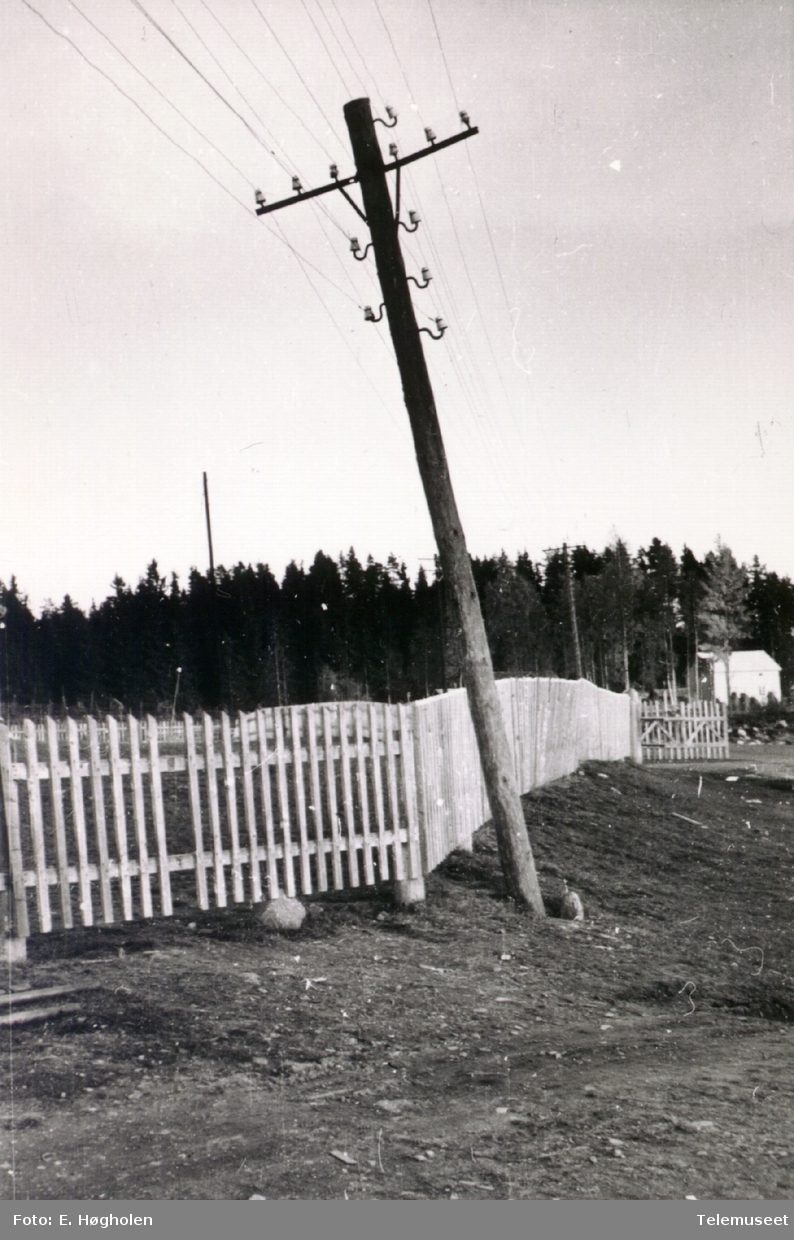 Telefonstolpe med slagside ved et gjerde, i nærheten av Åsbygda sentral Romedal i Stange.