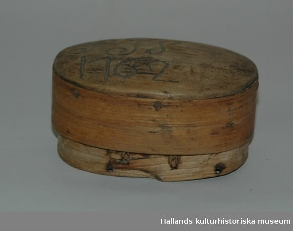 Oval dosa av furu i svepteknik. Svepen hopfästa med söm, både lock och ask. Botten ursprungligen fäst med träplugg. På locket märkt: "PJS 1762."