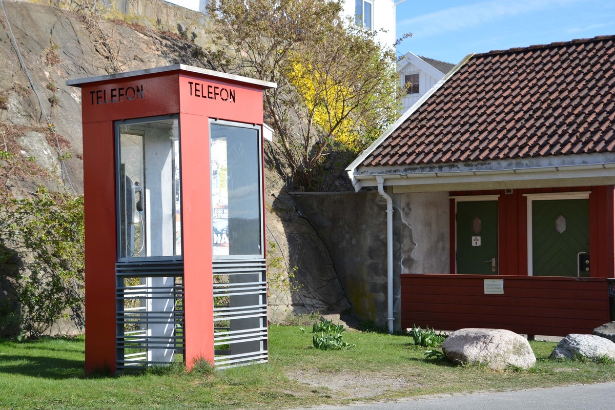 Telefonkiosken står på Drøbak båthavn, og er en av de 100 vernede telefonkiosker i Norge. De røde telefonkioskene ble laget av hovedverkstedet til Telenor (Telegrafverket, Televerket). Målene er så å si uforandret. 
Vi har dessverre ikke hatt kapasitet til å gjøre grundige mål av hver enkelt kiosk som er vernet. 
Blant annet er vekten og høyden på døra endret fra tegningene til hovedverkstedet fra 1933.
Målene fra 1933 var:
Høyde 2500 mm + sokkel på ca 70 mm
Grunnflate 1000x1000 mm.
Vekt 850 kg.
Mange av oss har minner knyttet til den lille røde bygningen. Historien om telefonkiosken er på mange måter historien om oss.  Derfor ble 100 av de røde telefonkioskene rundt om i landet vernet i 1997. Dette er en av dem.