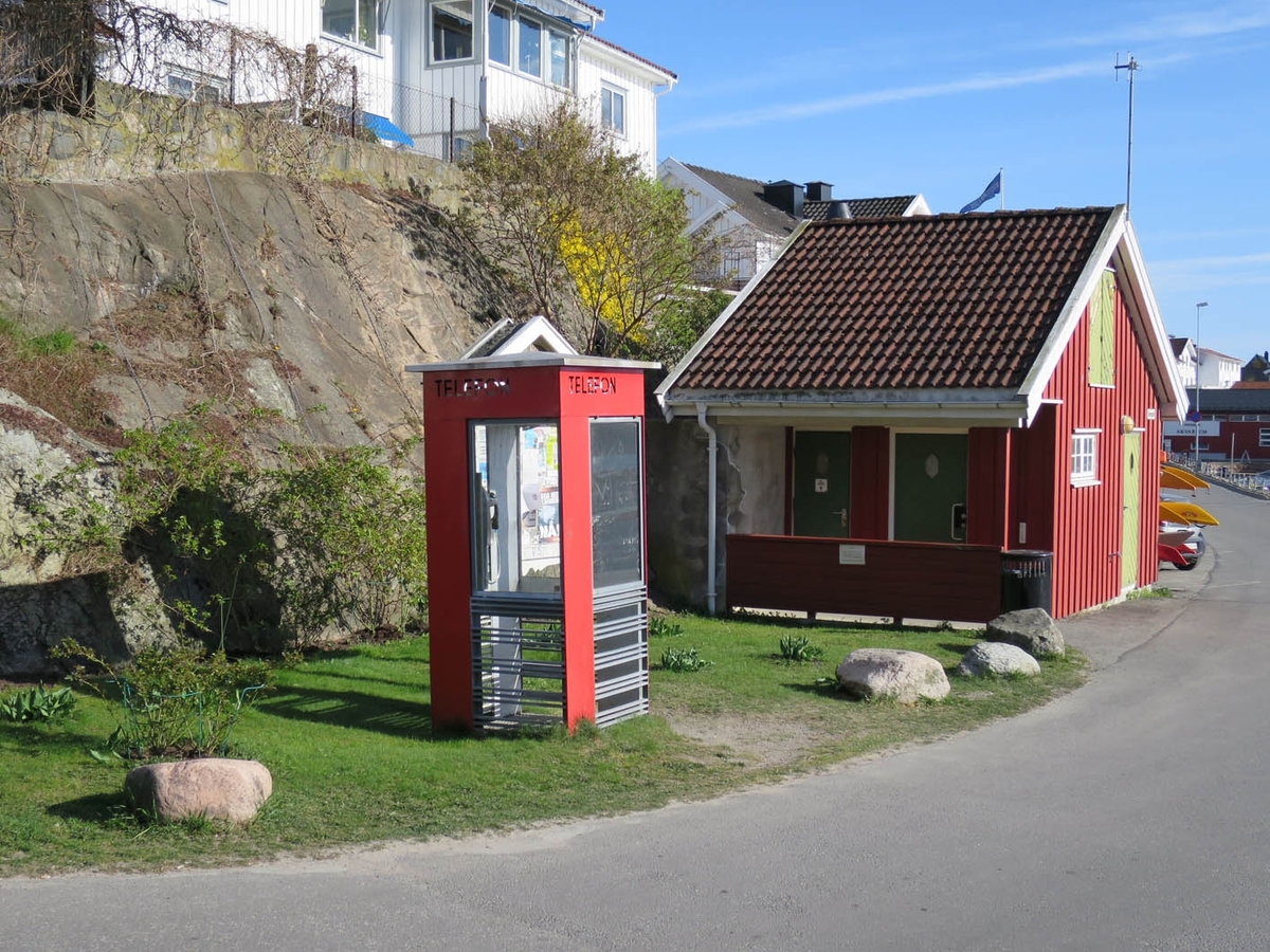 Telefonkiosken står på Drøbak båthavn, og er en av de 100 vernede telefonkiosker i Norge. De røde telefonkioskene ble laget av hovedverkstedet til Telenor (Telegrafverket, Televerket). Målene er så å si uforandret. 
Vi har dessverre ikke hatt kapasitet til å gjøre grundige mål av hver enkelt kiosk som er vernet. 
Blant annet er vekten og høyden på døra endret fra tegningene til hovedverkstedet fra 1933.
Målene fra 1933 var:
Høyde 2500 mm + sokkel på ca 70 mm
Grunnflate 1000x1000 mm.
Vekt 850 kg.
Mange av oss har minner knyttet til den lille røde bygningen. Historien om telefonkiosken er på mange måter historien om oss.  Derfor ble 100 av de røde telefonkioskene rundt om i landet vernet i 1997. Dette er en av dem.
