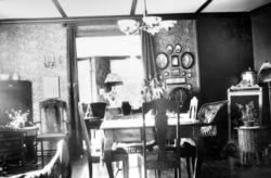 Fra en stue i motlys. Rommet er nyderlig tapetsert, og utsty