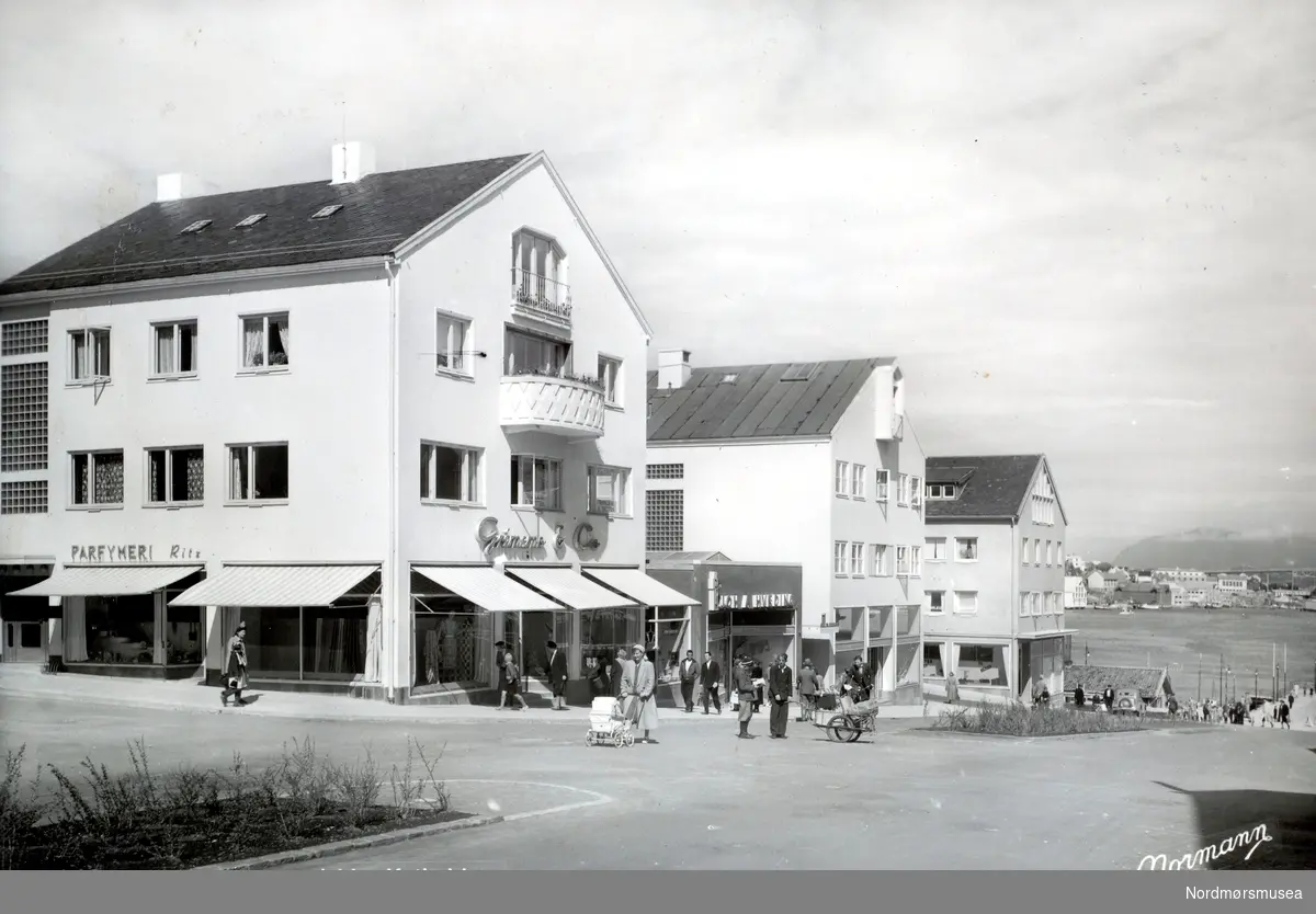 Postkort med tekst: ";Kristiansund N., Kaibakken."; Parfymeri Ritz i Nedre Enggate, Grimsmo &amp; Co,
 Hveding med ";lamell";. (Fra Nordmøre Museums fotosamlinger.)
