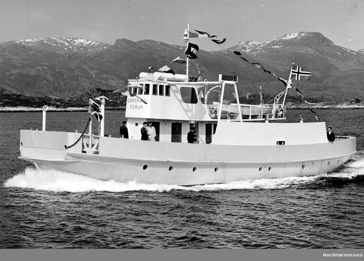 "Gurskøyferja" ble bygd i 1958 for L/L Volda-Folkestad Bilferje. Den hadde plass til 10 biler og ble satt inn ruta Eiksund-Rjånes-Berknes-Velsvik. 1. januar 1962 ble dette ferjeselskapet overtatt av Møre og Romsdal fylkesbåtar (MRF) som byttet navnet til Fausa". Ferja gikk i ulike samband i Møre og Romsdal til 1982 da den ble solgt. Kilde: Torvik, A. I. (2000). Om samferdsel i Møre og Romsdal : Møre og Romsdal fylkesbåtar 1920-1995 : D. 2 : Samfunn og ferdsel (Vol. D. 2). Molde: Møre og Romsdal fylkesbåtar. (Info: Sveinung Berild)  - Gurskøy ligger delvis i Herøy kommune og delvis Sande kommune på SUnnmøre.  Datering og fotograf er ukjent. Fra Nordmøre museums fotosamlinger.