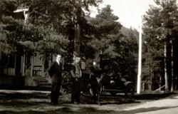 Foto av en gruppe menn stående ved siden av en bil, mens lik