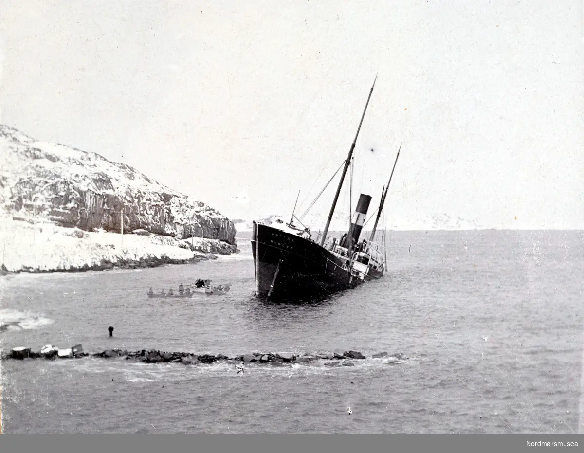 S/S Nordens stranding i Sørsundet 12. februr 1903. Det var storm- og strømforhold som var årsaken til at den ikke fikk legge til kaien. "Norden" som kom til Kristiansund med en saltlast, losset restpartiet på Hammervoldbrygga i Sørsundet. Ved avgangen var det stormbyger fra Nordvest så skipet greide ikke å avansere men drev ned mot sørspissen av Innlandet. Rutebåten "Nordmøre" forsøkte å assistere, men greide det ikke. "Norden" gikk på grunn med akterenden på Lervikskjæret på Innandet, og sank. Den ble provisorisk tettet og flyttet til Hønebukta, derifra til Trondheim og videre til Bergen. Dens senere skjebne er ukjent. Fotograf er her trolig Ole Olsen Ranheimsæter. Fra Nordmøre museums fotosamlinger. variant