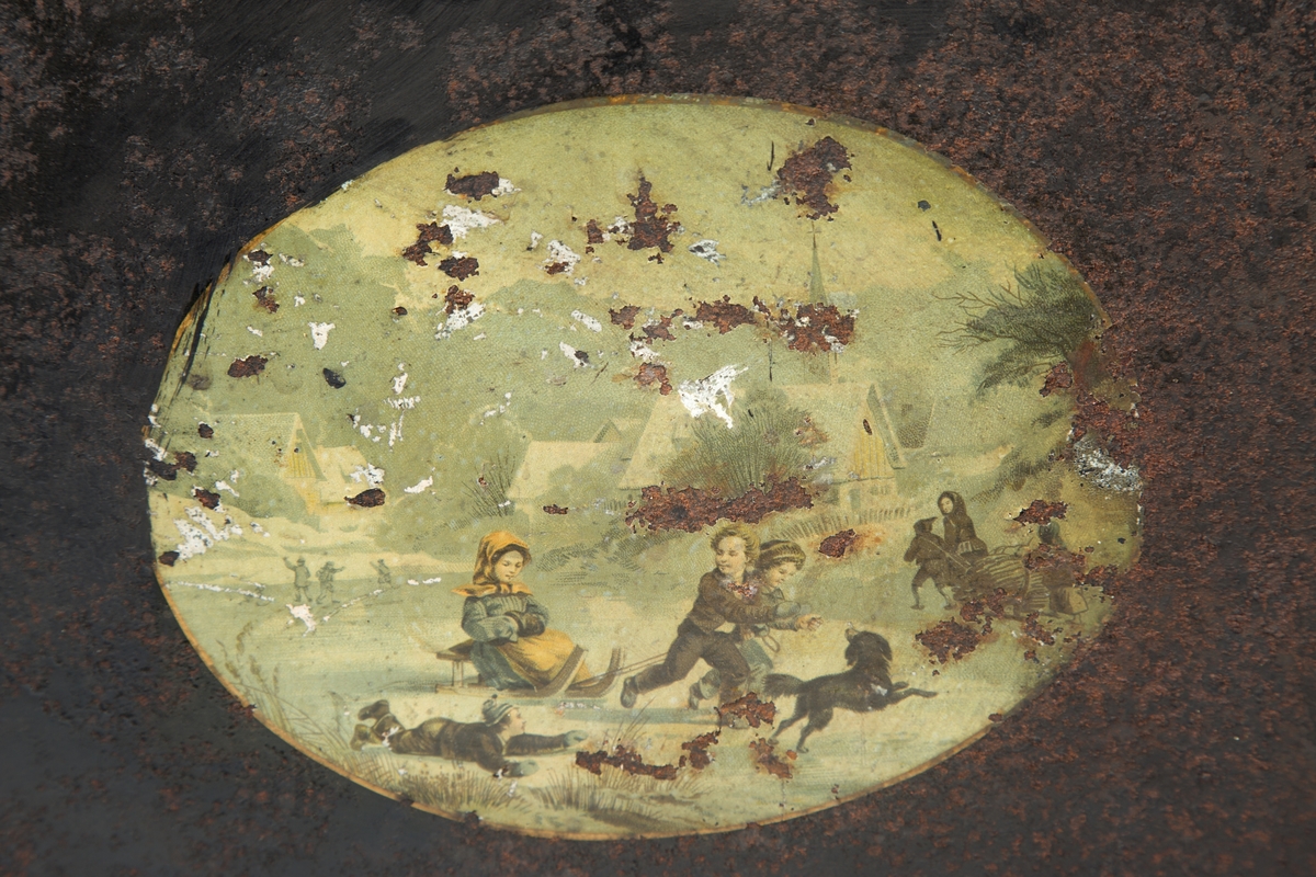 Liggende, ovalt motiv av lekende barn i vinterlandskap.