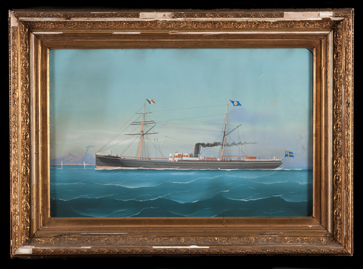 Ångfartyget Nautilus, skonertriggad med beslagna segel, svart skrov, svart skorsten, på förtoppen italiensk flagg, på stortoppen bolagsflagg, svensk unionsflagg på flaggspel. Vesuvius i bakgrunden