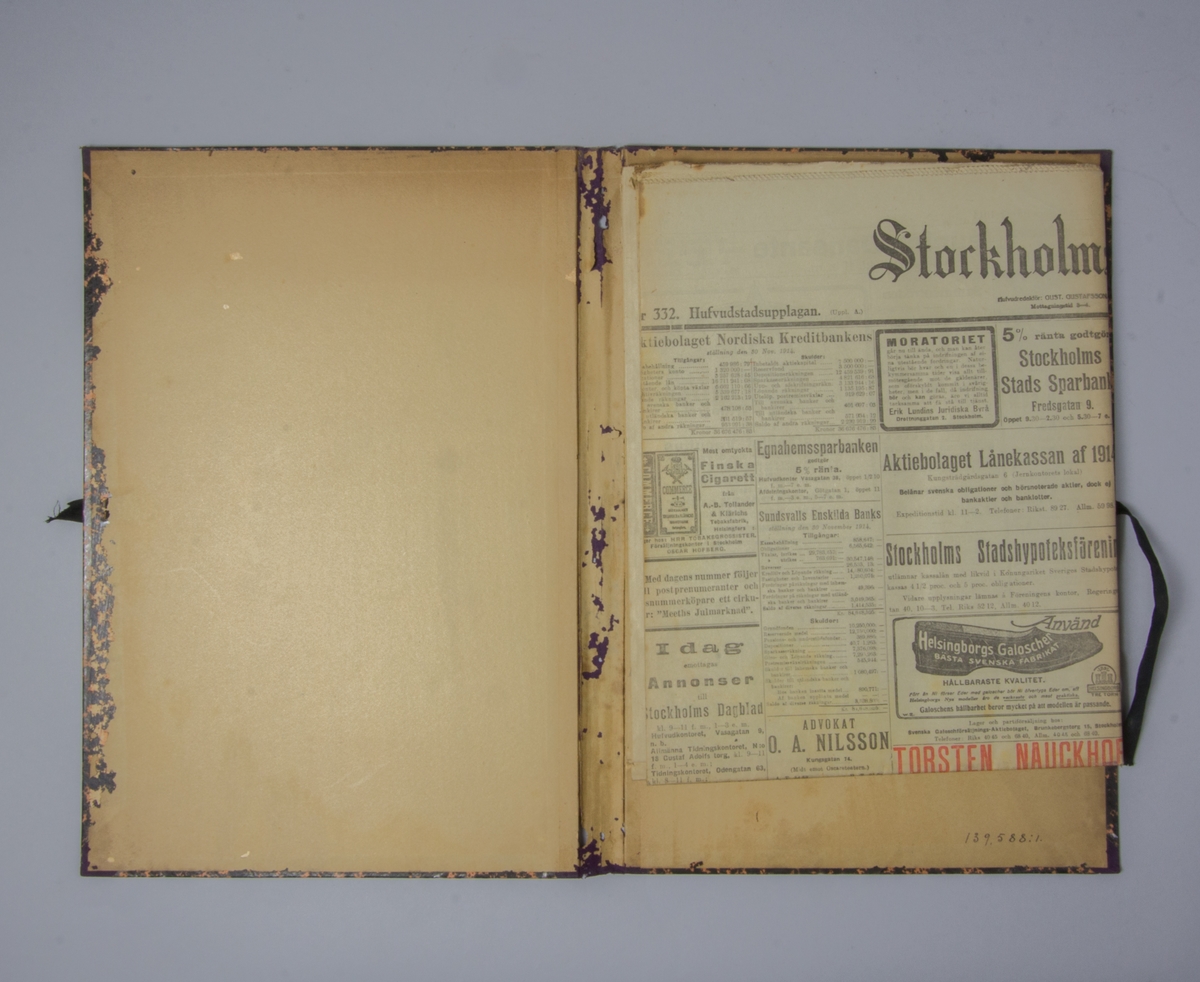 Portfölj av marmorerad papp. Sammanhållen med knytband. Rygg av lila linne. Innehåller enbart flera exemplar av Stockholms Dagblad från 1914.