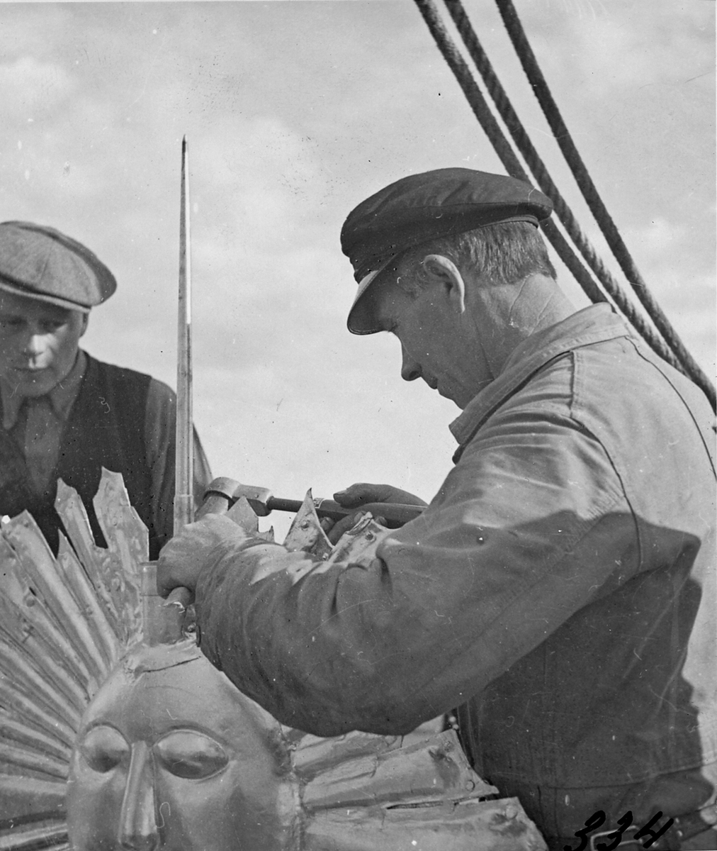 Plåtmästare E. Birath monterar åskledare till kyrktornet 1935.