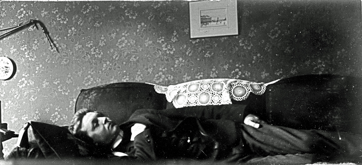 En man som ligger på en soffa. Fotograf Alfred Bergendahl. Givare H Bergendahl.