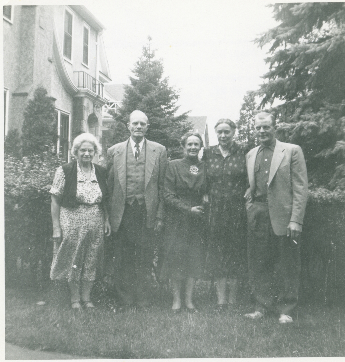 3 kvinner og 2 menn er avbildet utenfor et bolighus i Minneapolis, Amerika. Mannen lengst til høyre er Arnfinn Rosenlund (født i 1918)