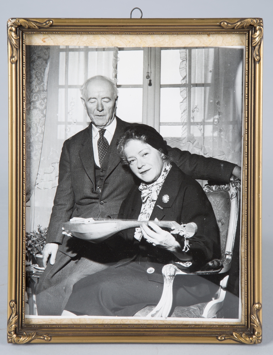 Bildet viser Victoria Bachke og hennes mann Ivar Skjånes. De sitter i Privatboligen. 
victoria holder et strengeinstrument.