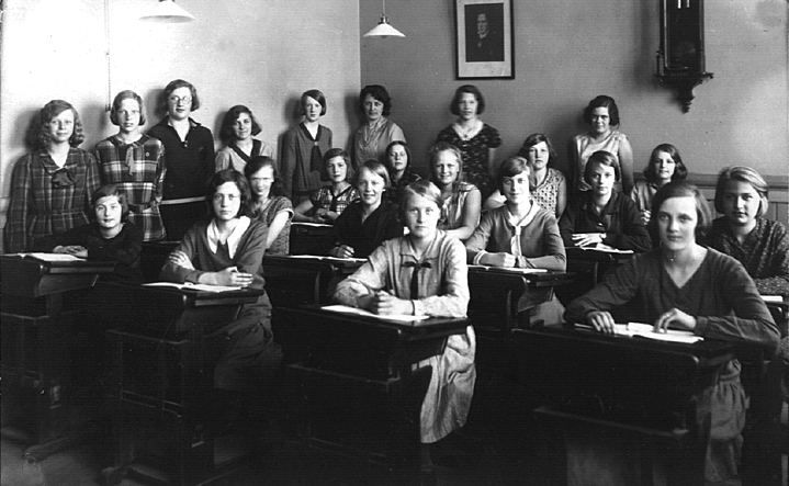 Foto av en klass i Flickskolan, i en skolsal.