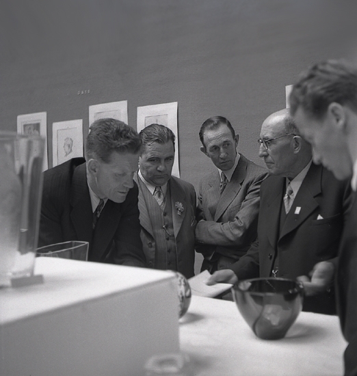 Glasets dag. Smålands Museum. Några herrar diskuterar något vid ett av borden i glasutställningen.