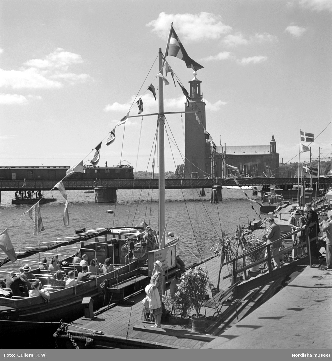 Stockholm. Turistbåtar vid Tegelbacken, Norra järnvägsbron och Stadshuset i bakgrunden.