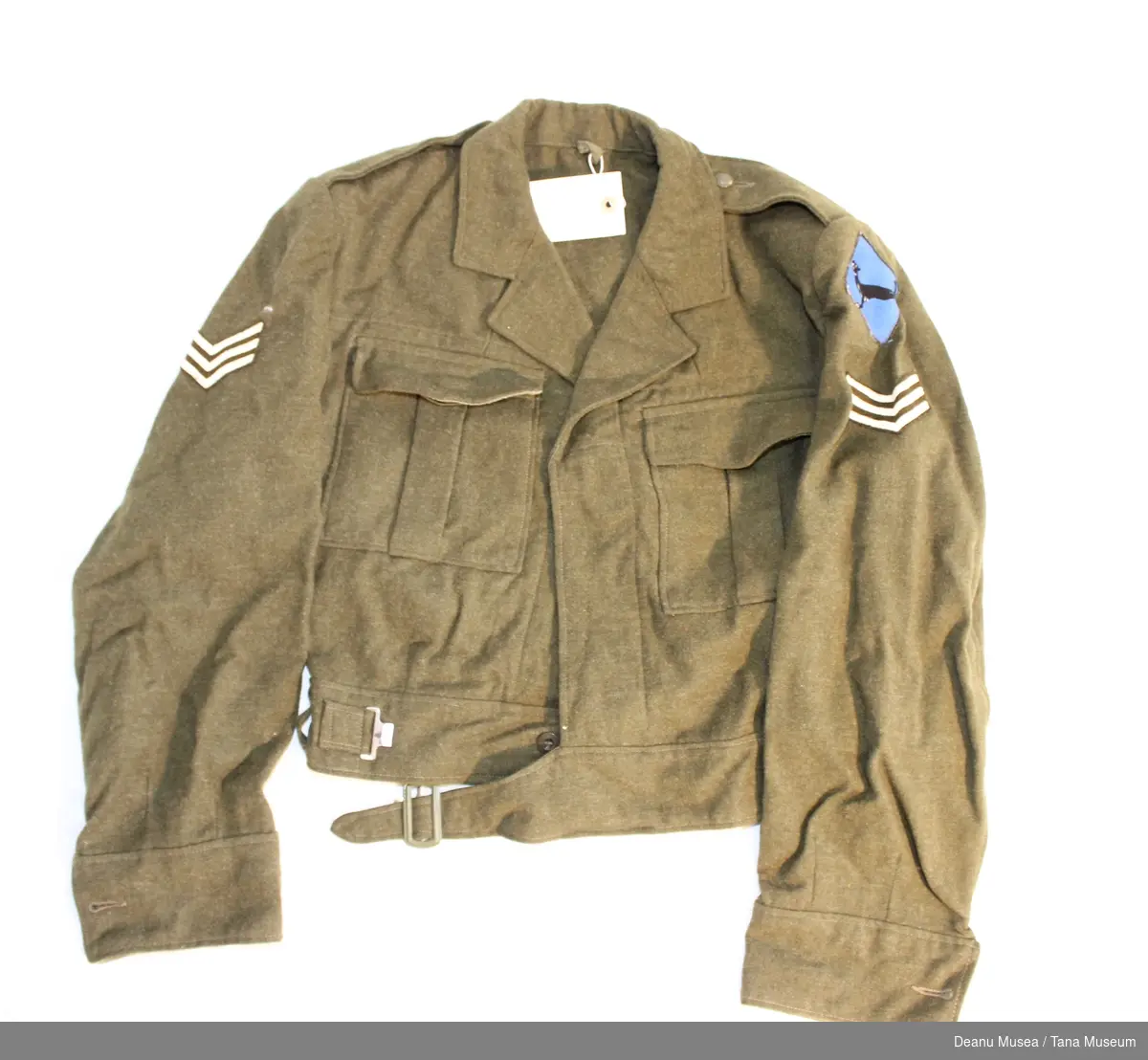 Uniformsjakke i vadmel med sersjant distinksjoner på skuldrene samt Varanger bataljonens emblem på den ene skulderen.