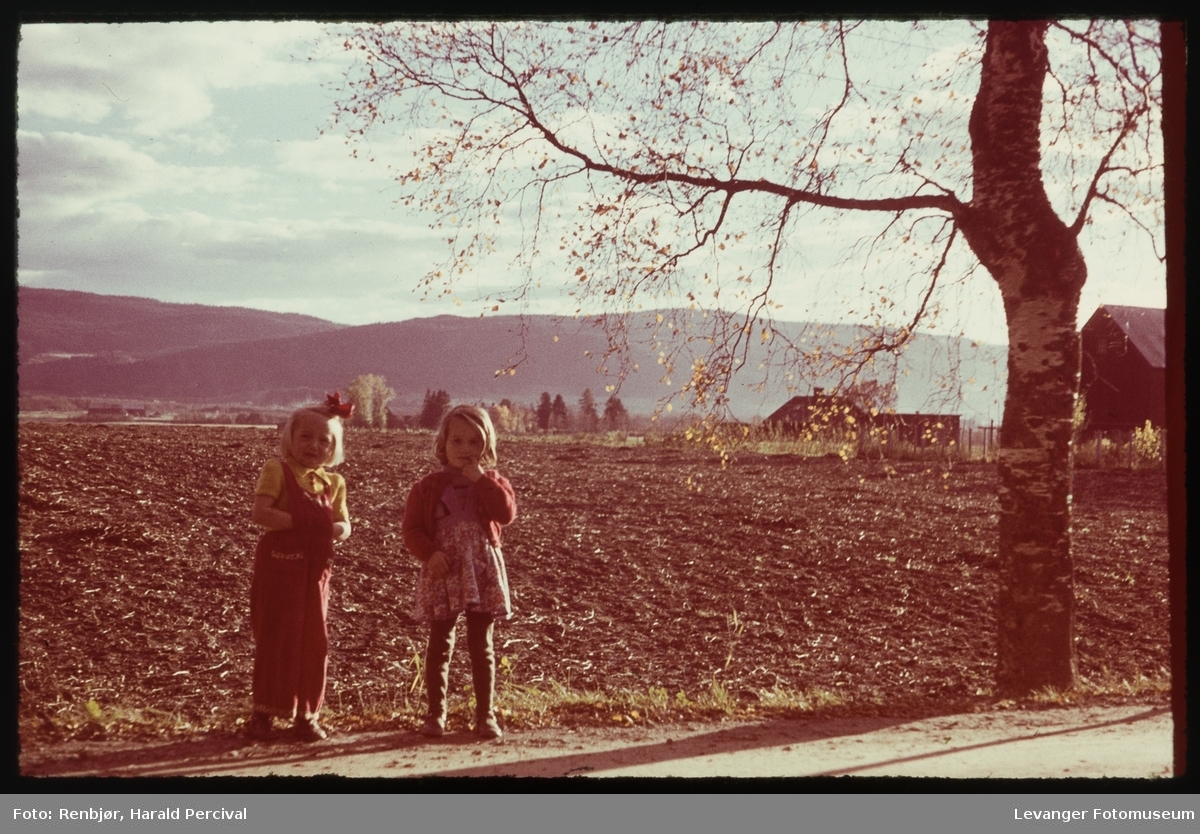 Foto av Inger Eva Lyng og Aslaug Hofstad stående på vegkanten. I høyre bildekant skimtes husene på gården Stiklestad østre, Verdal