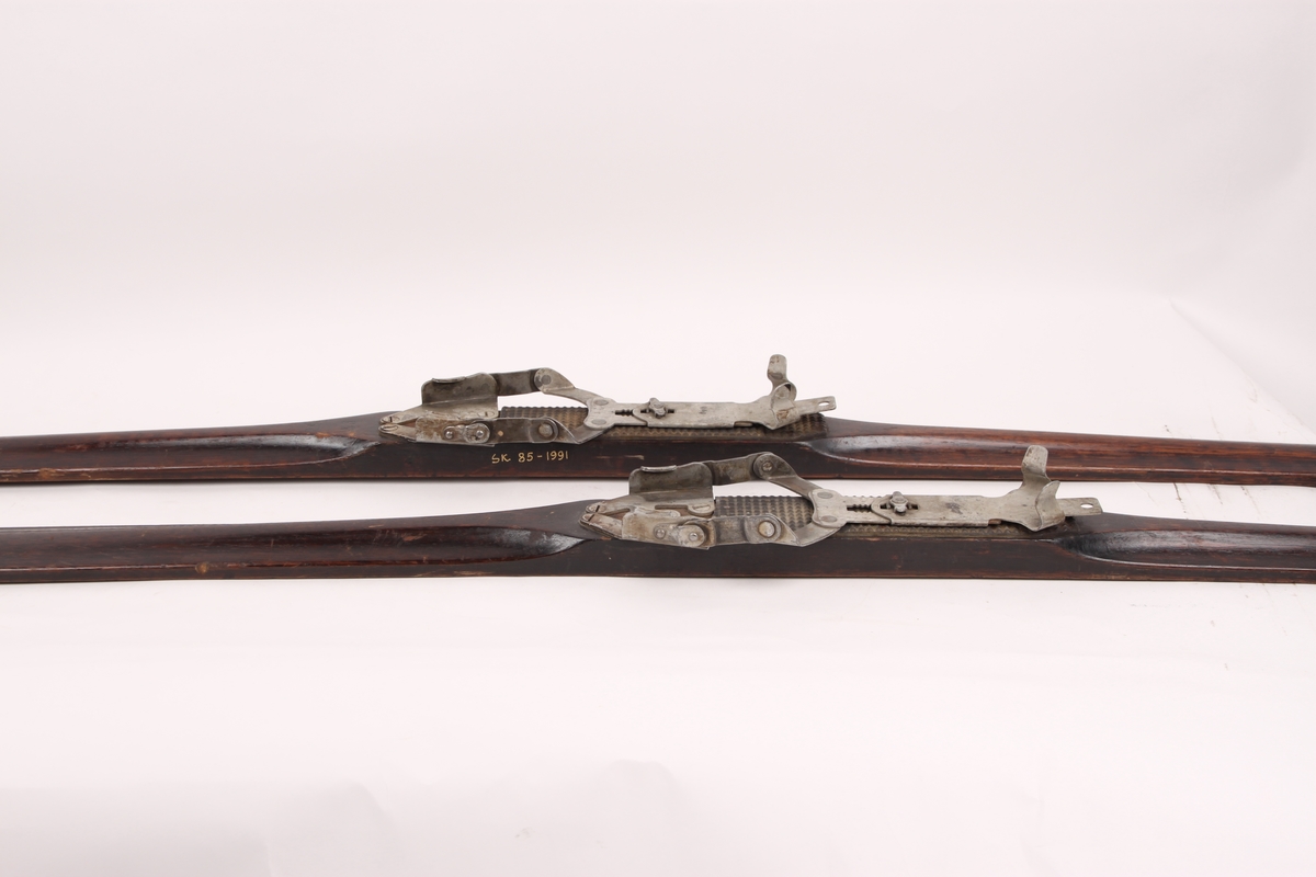 Turskiski i helved hickory, beiset og lakket på oversiden, og tjæret under. Skiene har sukkerbit-tupp, hulkilformet rygg og rand på undersiden. Fotstegplate av riflete svart linoleum, festet med stifter. Skiene har Automatic binding, Tappe´s patent. På skiene er det festet en etikett trolig i forbindelse med transport.