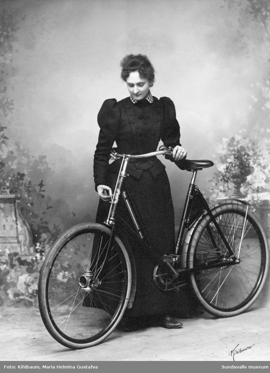 Porträtt av fotograf Maria Kihlbaum i hennes ateljé. Det ansågs djärvt och lite okvinnligt att cykla för en dam.
Enligt uppgift så tillhörde Maria en av de första kvinnliga cyklisterna i Sundsvall. Bild 1 visar kopian och bild 2 glasnegativet.