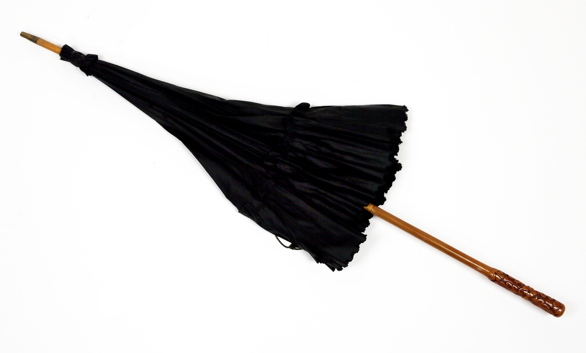 Paraply eller parasoll av tre med utskåret håndtak og kypertvevd svart stoff med en rynkekant ytterst