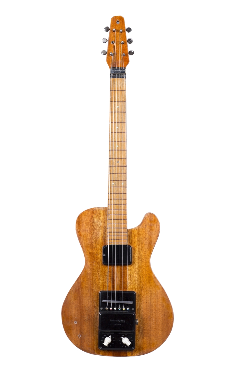 Elektrisk gitar med kropp og hals av mahogny. Magnet ved halsfeste og pickup ved strengefeste (NilsensSystem). Kontrollere for tilpasning og klangfarge. Tilpasning tilsvarer volum og gir størst volum på nivå 1. Enkelte av stemmeskruene er ikke originale.